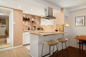 A modern kitchen with a central island, bar stools, and a brick backsplash. - Fogd Drejers Gate – Tromsø City Centre (Tromsø)