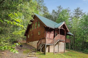 A wooden cabin with a balcony, surrounded by trees. - Romantic Cabin | Sauna & Hot Tub near Dollywood (Sevierville)