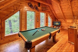 A wooden room with a pool table, large windows, and a television. - Romantic Cabin | Sauna & Hot Tub near Dollywood (Sevierville)