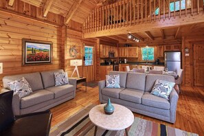 A log cabin interior with a living room, kitchen, and dining area. - Romantic Cabin | Sauna & Hot Tub near Dollywood (Sevierville)