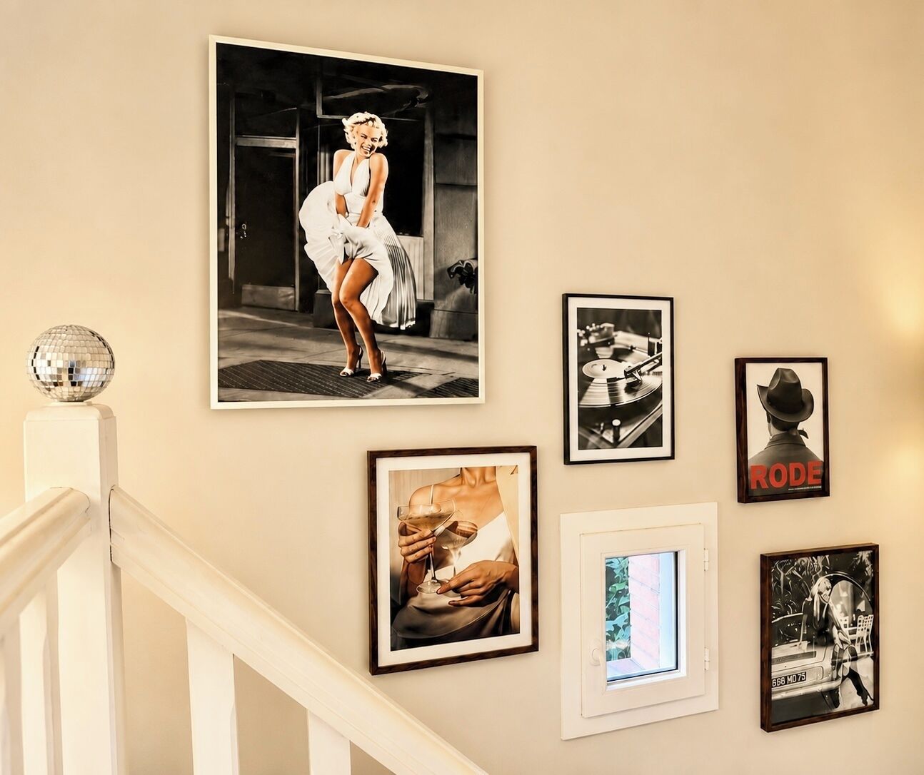 Eine Wand mit verschiedenen gerahmten Fotografien und einer Discokugel.