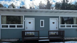 A single-story mobile home with two doors, a small window, and a porch with benches. - Cozy 1BR hotel room, Hamilton - #328 Susquehanna (Hamilton)