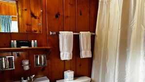 A bathroom with wooden paneling, a sink, a toilet, and a shower curtain. - Cozy 1BR hotel room, Hamilton - #328 Susquehanna (Hamilton)