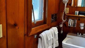 A wooden-paneled bathroom with a window, a hairdryer, a sink, and a towel rack. - Cozy 1BR hotel room, Hamilton - #328 Susquehanna (Hamilton)