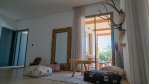 Habitació amb un mirall gran, una taula de fusta, un sofà i vista a l'exterior.