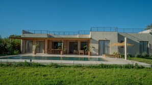 Una casa moderna amb piscina, zona d'estar a l'exterior i terrassa coberta.