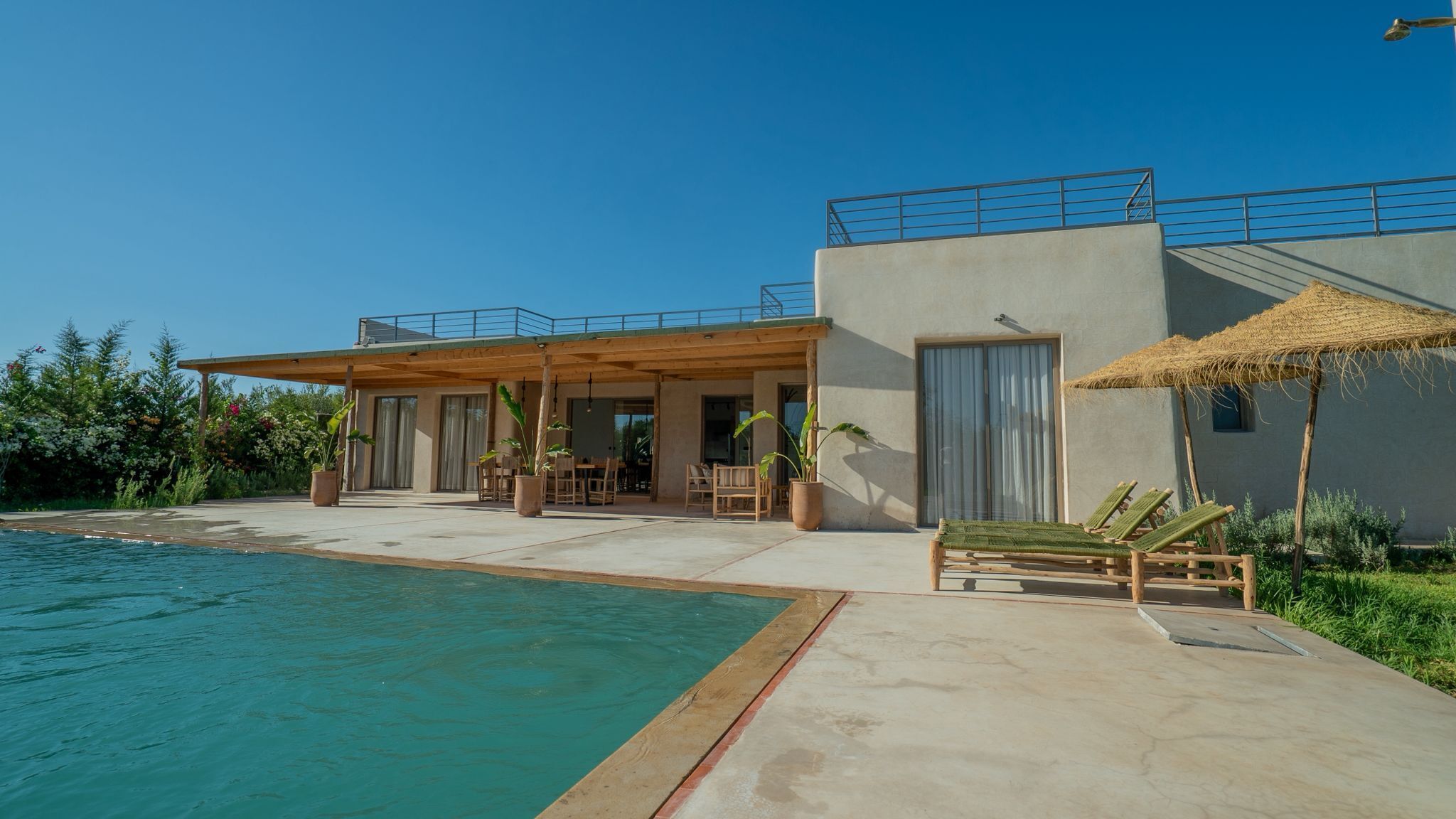 Une maison moderne dotée d’une piscine, d’un espace salon extérieur et d’un patio couvert.