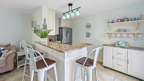 A kitchen with a central island, white cabinets, a refrigerator, and a bar stool seating area. - SummerSalt - 5 Min Walk To Beach! (Jupiter)