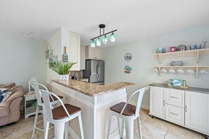 A kitchen with a central island, white cabinets, a refrigerator, and a bar stool seating area. - SummerSalt - 5 Min Walk To Beach! (Jupiter)