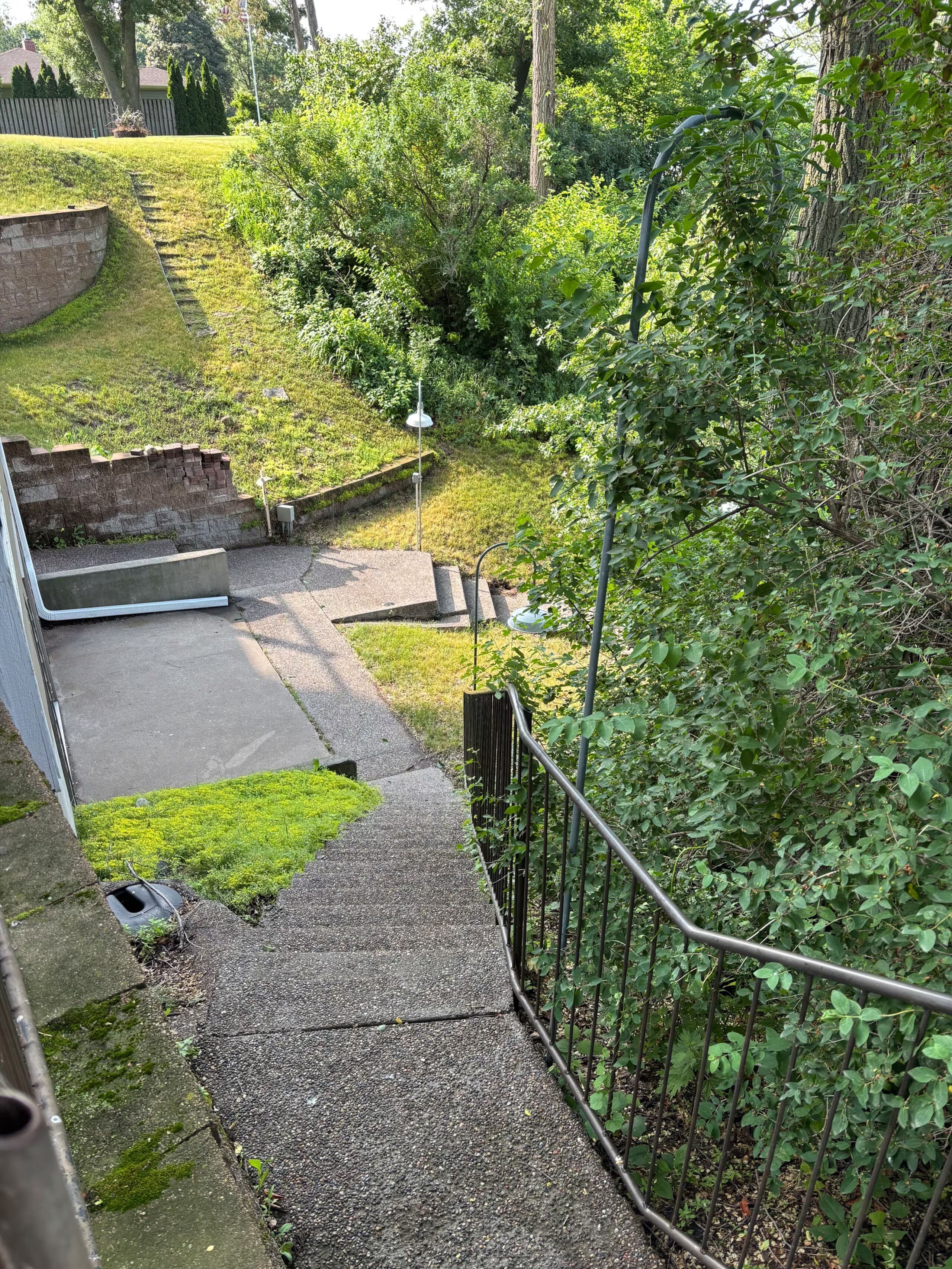 A pathway leading to a grassy area with a metal railing and a lamp post.
