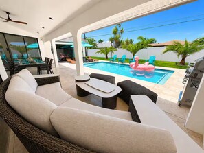 Un espace de vie extérieur moderne comprenant une piscine, des chaises longues et un coin repas.