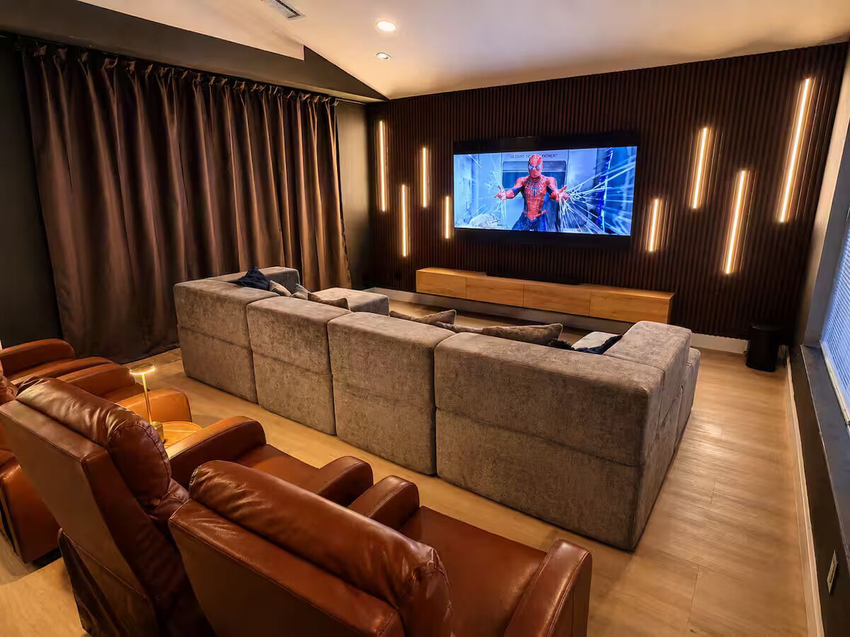 Una sala de estar moderna con un sofá modular, sillones de cuero y un televisor de pantalla plana montado en la pared.