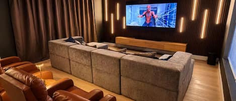 Una sala de estar moderna con un sofá modular, sillones de cuero y un televisor de pantalla plana montado en la pared.