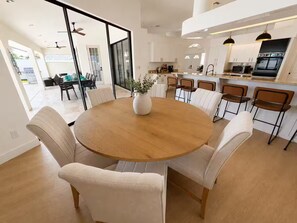 Une cuisine moderne avec des meubles blancs, un îlot central et un coin repas comprenant une table ronde et des chaises.