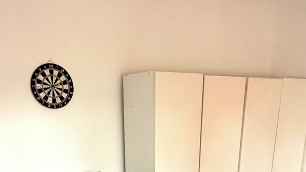 A bedroom with a bed, a dresser, a wardrobe, and a dartboard on the wall. - Apartment Sleeps 6 With Wifi in Willesden Green (London)