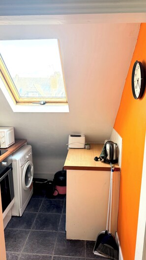 Eine kleine Küche mit Waschmaschine, Toaster und einem kleinen Fenster.