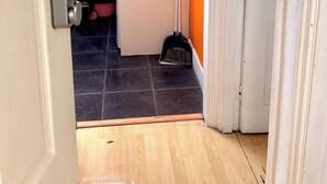 A narrow hallway leading to a room with a window, a door with a telephone, and a small kitchenette area with a sink and a kettle. - Apartment Sleeps 6 With Wifi in Willesden Green (London)