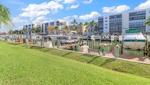 A marina with boats docked, a grassy area, and modern buildings in the background. - 2-bedroom, 2 floor condo in beautiful Fort Myers Beach! (Fort Myers Beach)