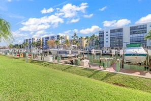 A marina with boats docked, a grassy area, and modern buildings in the background. - 2-bedroom, 2 floor condo in beautiful Fort Myers Beach! (Fort Myers Beach)