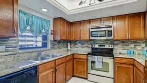 A kitchen with wooden cabinets, a stainless steel microwave, a stove, and a dishwasher. - 2-bedroom, 2 floor condo in beautiful Fort Myers Beach! (Fort Myers Beach)