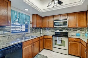 A kitchen with wooden cabinets, a stainless steel microwave, a stove, and a dishwasher. - 2-bedroom, 2 floor condo in beautiful Fort Myers Beach! (Fort Myers Beach)
