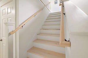 Un escalier avec des marches et des rampes en bois, menant à un palier doté d’une porte.
