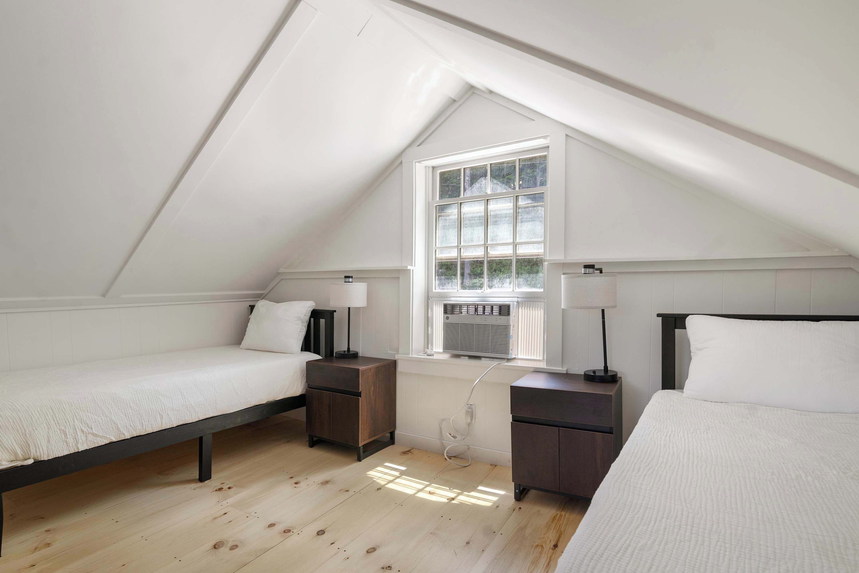 Un dormitorio con dos camas individuales, una ventana con persianas y un ventilador de techo.