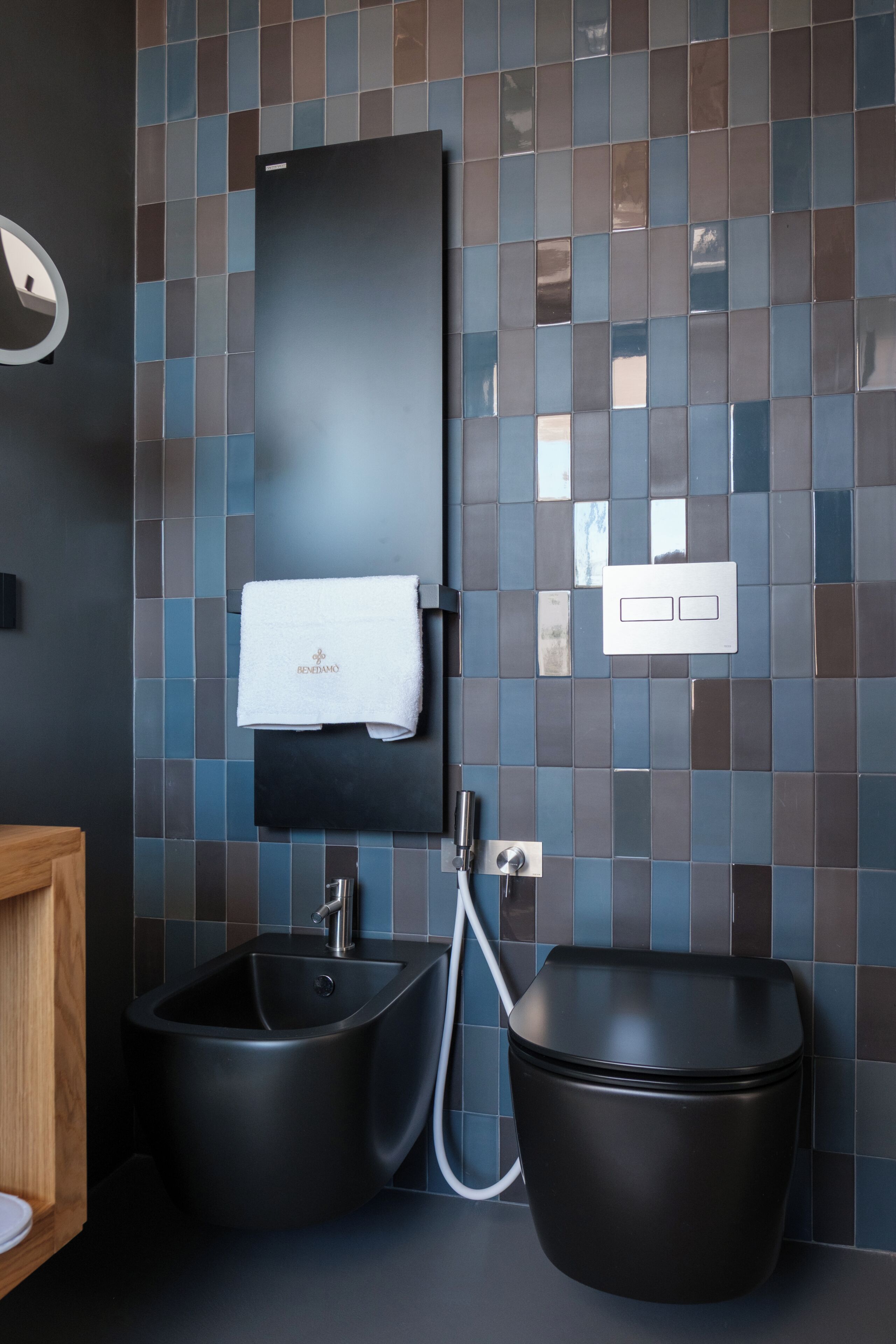 Ein modernes Badezimmer mit einem schwarzen Waschbecken, einer schwarzen Toilette und einem Handtuch an einem Wandhalter.