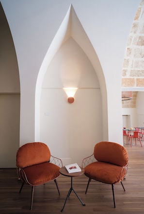 A modern interior with two cushioned chairs, a small table, and a unique arched ceiling design. - Benedamò Home Inside (Polignano a Mare)