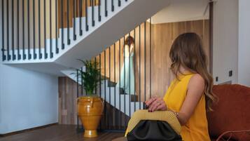 A woman sitting on a sofa in a modern interior with a staircase and a large vase.