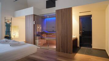 A modern bedroom with a large bed, a glass-enclosed walk-in closet, and a visible bathroom with a bathtub.