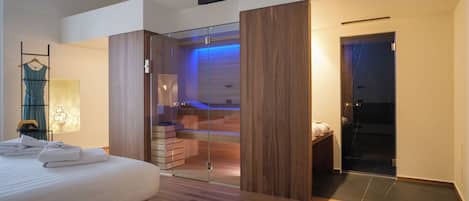 Quarto moderno com uma cama grande, um closet espaçoso com portas de vidro e um banheiro visível com banheira.