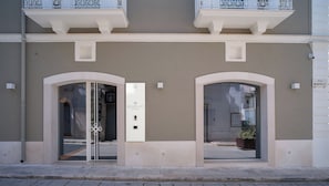 A building facade with two arched doorways, a sign with the number 36, and a small potted plant near the entrance.