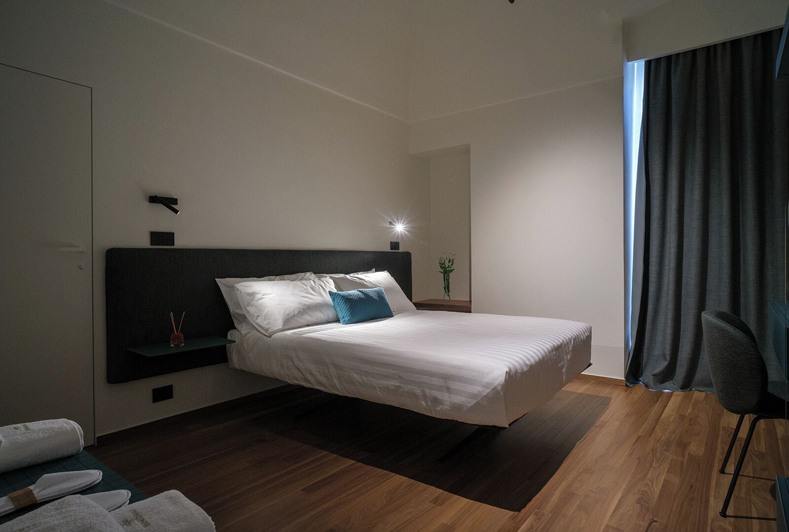 Un dormitorio moderno con una cama grande, una mesita de noche, una silla y vistas al exterior.