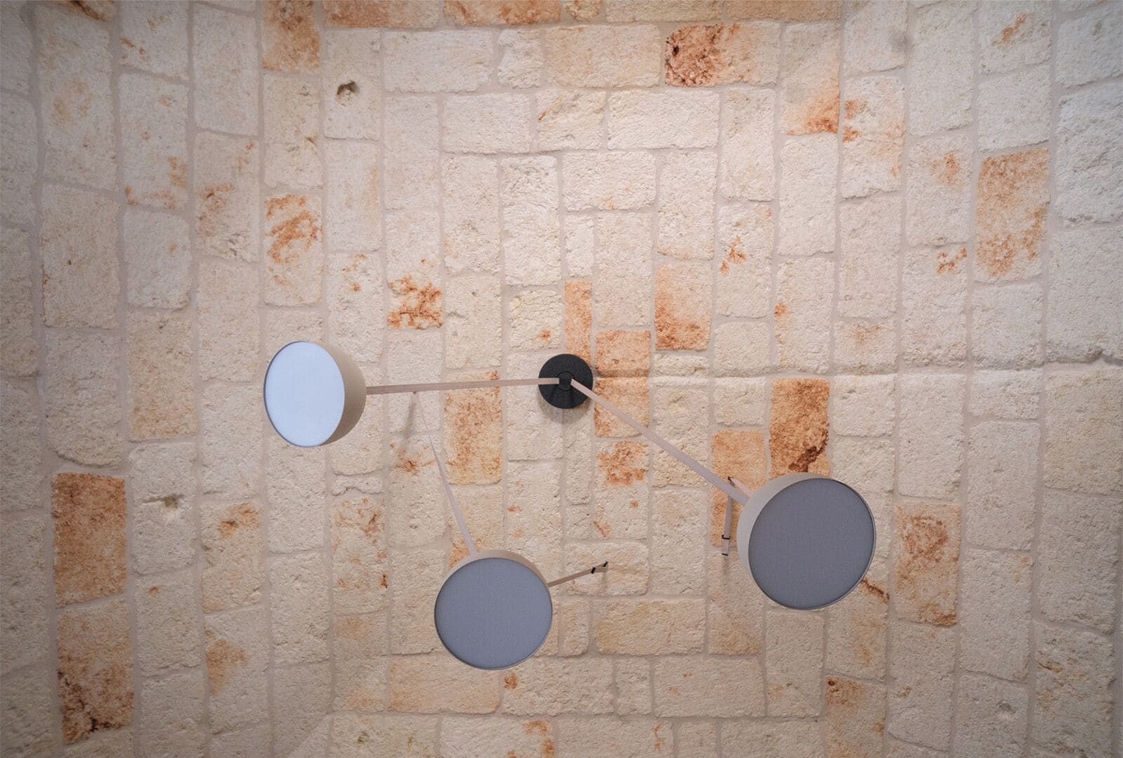 A wall with a brick pattern and three circular fixtures.