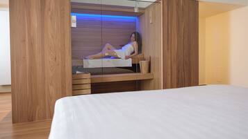 Quarto moderno com cama embutida, painéis de madeira e um pequeno espaço de estar com uma pessoa.