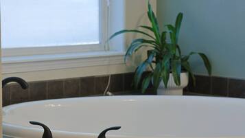 Une salle de bain avec une baignoire, une fenêtre et une plante en pot.