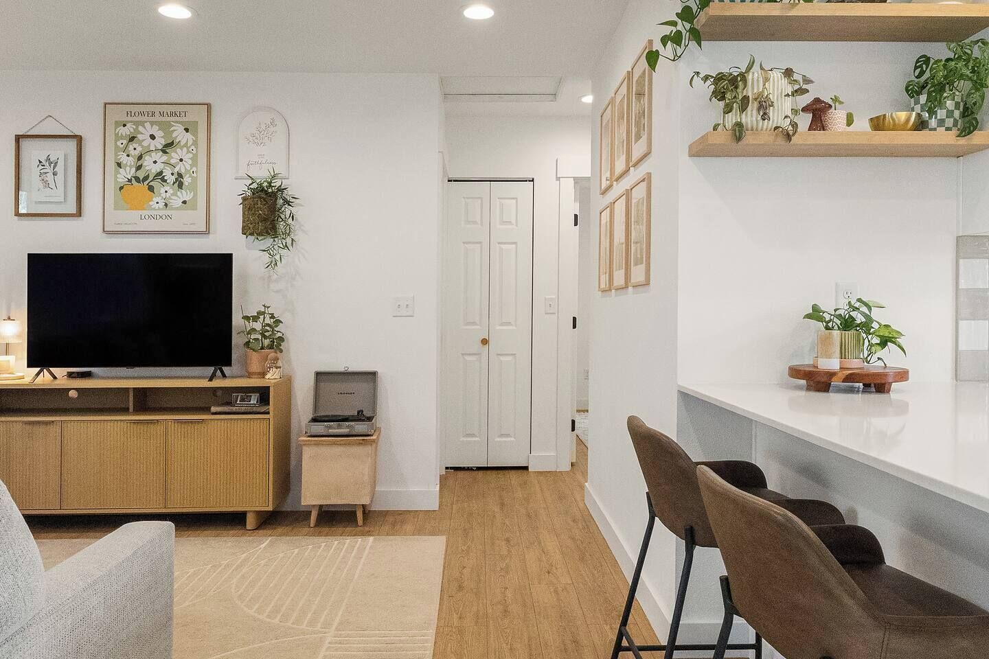 A living room with a flat-screen TV, wooden entertainment unit, and a small table with a record player.
