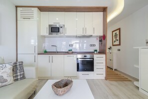 Eine kleine Küche mit weißen Schränken, einer Mikrowelle, einem Backofen und einem Spülbecken.