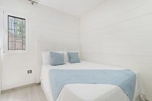 Ein Schlafzimmer mit einem Bett, einem Fenster und Blick auf eine Treppe vor dem Haus.