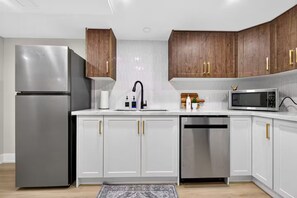Une cuisine moderne avec des meubles blancs, des appareils en acier inoxydable et des meubles hauts en bois.