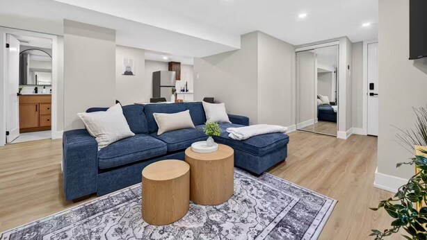 Een moderne woonkamer met een blauwe modulaire bank, twee houten bijzettafeltjes en een kamerbreed tapijt met een patroon.