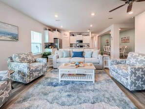 A living room with a sofa, coffee table, and patterned chairs. - NEW! 5BR WindMark | Golf Cart | Pet Friendly (Port St. Joe)