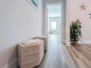 A hallway with a light-colored floor, a potted plant, and a starfish decoration on the wall. - NEW! 5BR WindMark | Golf Cart | Pet Friendly (Port St. Joe)