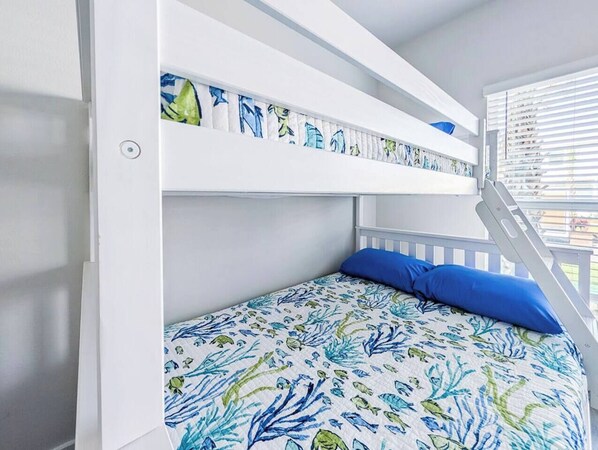 A bunk bed with a patterned bedspread and a blue pillow.