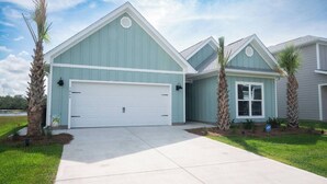A two-story building with a garage, a covered entryway, and a landscaped front yard with palm trees.