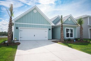 A two-story building with a garage, a covered entryway, and a landscaped front yard with palm trees.