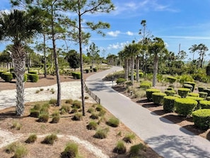 A landscaped pathway with trimmed hedges and trees, leading through a park-like setting. - NEW! 5BR WindMark | Golf Cart | Pet Friendly (Port St. Joe)