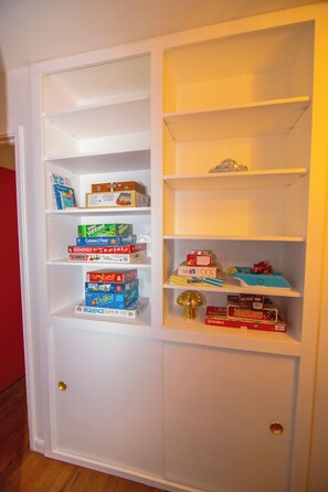 Et hvidt opbevaringsrum med mange hylder fyldt med diverse brætspil.