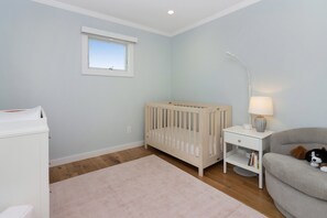 A baby room with a crib, a changing table, a sofa, and a nightstand with a lamp.